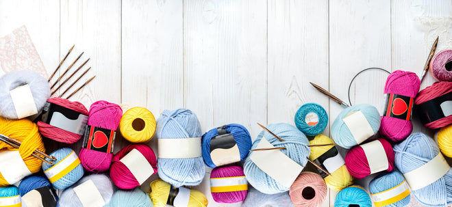 Spritzschutz - Wolle und Stricknadeln auf Holzhintergrund