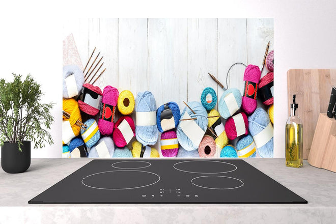 Spritzschutz - Wolle und Stricknadeln auf Holzhintergrund