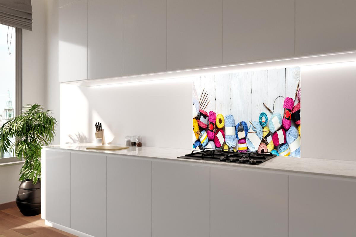 Spritzschutz - Wolle und Stricknadeln auf Holzhintergrund